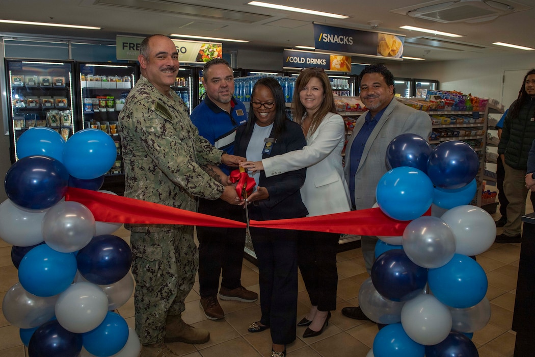 Capt. Jon Hopkins, Commander, Fleet Activities Yokosuka (CFAY), left, poses for a group photo with installation housing director and Navy Exchange Service Command representatives during a ribbon-cutting ceremony for the opening of a NEX Micro Mart in unaccompanied housing Building 3333 at CFAY, May 5, 2026. The NEX Micro Mart enhances quality of life by providing Sailors convenient access to food and essential items within their building.