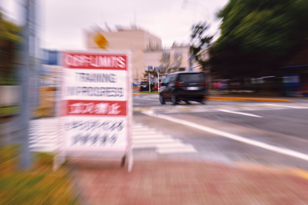 A vehicle passes a Training in Progress sign inside Fleet Activities Yokosuka, Japan's Carney Gate May 21, 2026 during the installation's Command Assessment of Readiness and Training (CART). The vehicle is unrelated to the assessment but is intended to illustrate a simulated gate runner drill designed to evaluate installation security forces' knowledge and response. CART is part of the Commander, Navy Installations Command (CNIC) Navy Security Force shore assessment and certification cycle. This cycle occurs over a three-year span and is broken into three phases: CART, the Regional Assessment (RASS), and the Final Evaluation Problem (FEP).