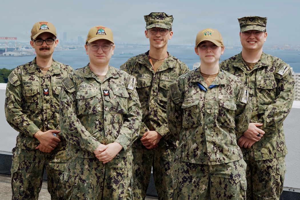(Front row from left to right) Aerographer's Mate 2nd Class Celestial Wilson, Airman Sara Clark, (second row from left to right) Aerographer's Mate 1st Class Batuhan Vural, Airman Recruit Corey Ogle, and Airman Andie Miller all of Naval Oceanography Anti-Submarine Warfare Center (NOAC) Yokosuka pose on top of the command's local headquarters with Tokyo Bay in the background May 27, 2026. The NOAC Yokosuka team tracks the weather to protect Fleet Activities Yokosuka Sailors, military families, and the places they live and work while serving as a critical resource for asset protection and risk management for Commander, U.S. Naval Forces Japan/Region Japan (CNFJ/RJ) ashore forces and U.S. 7th Fleet afloat personnel and ships.