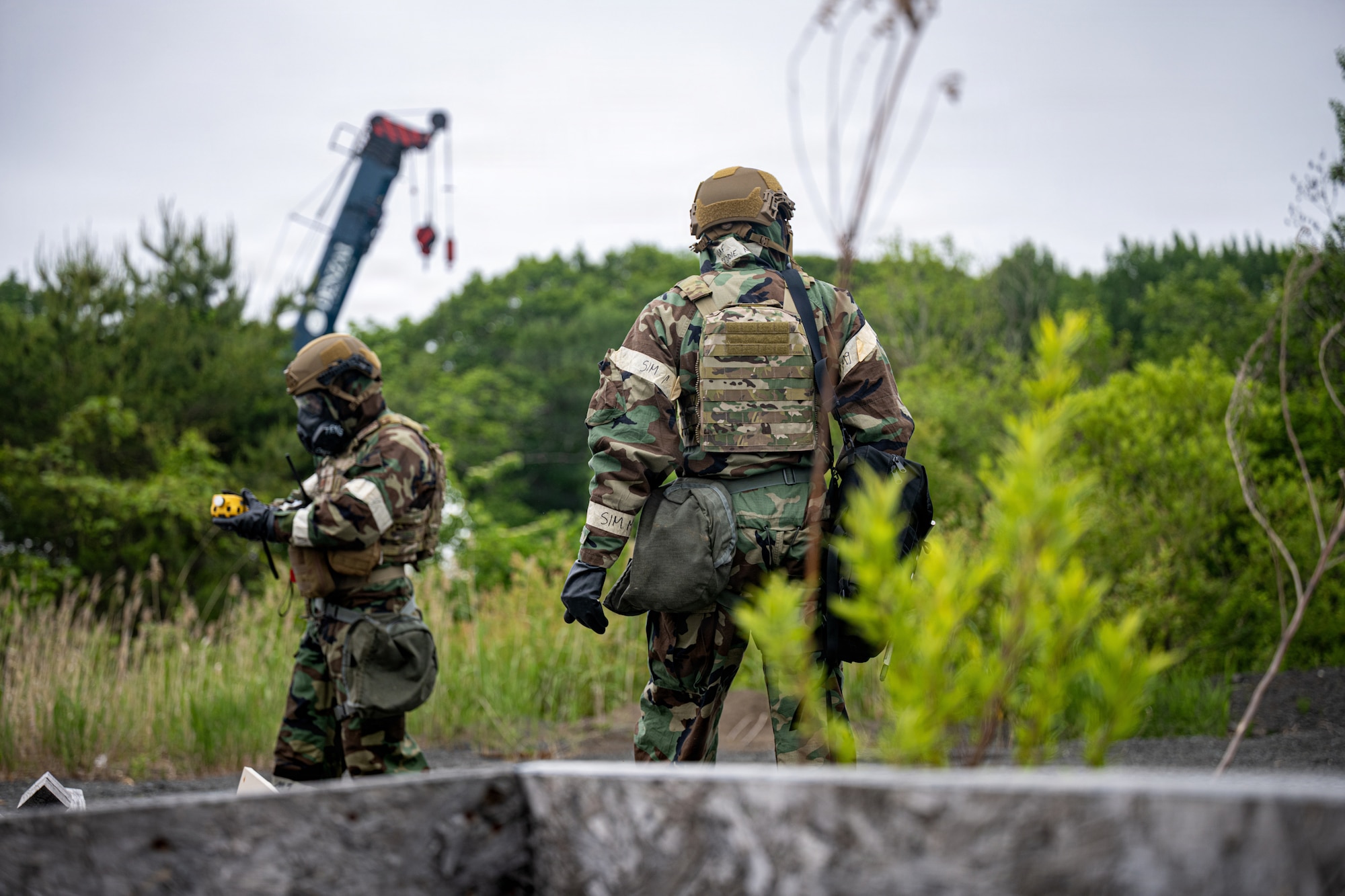 U.S. Air Force Staff Sgt. James Fink, left, 35th Civil Engineer Squadron (CES) emergency management noncommissioned officer in charge of logistics and training, and Senior Airman Nicholas Peddie, 35th CES emergency management technician, scan their surroundings for a simulated drone during a chemical, biological, radiological and nuclear training.