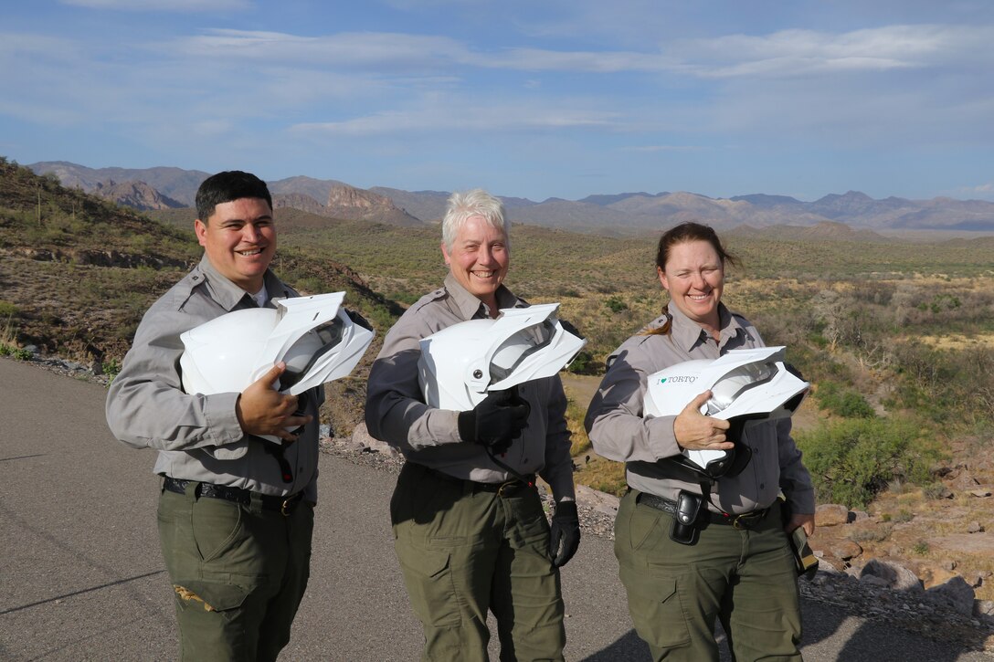 From left, Joseph Carranza Escobar, Marlene Schmitt and Emily Hibbard, park rangers with the U.S. Army Corps of Engineers, pose with their ATV helmets before preforming an environmental inspection of the Whitlow Range Dam Area May 13 near Queen Valley, Arizona.