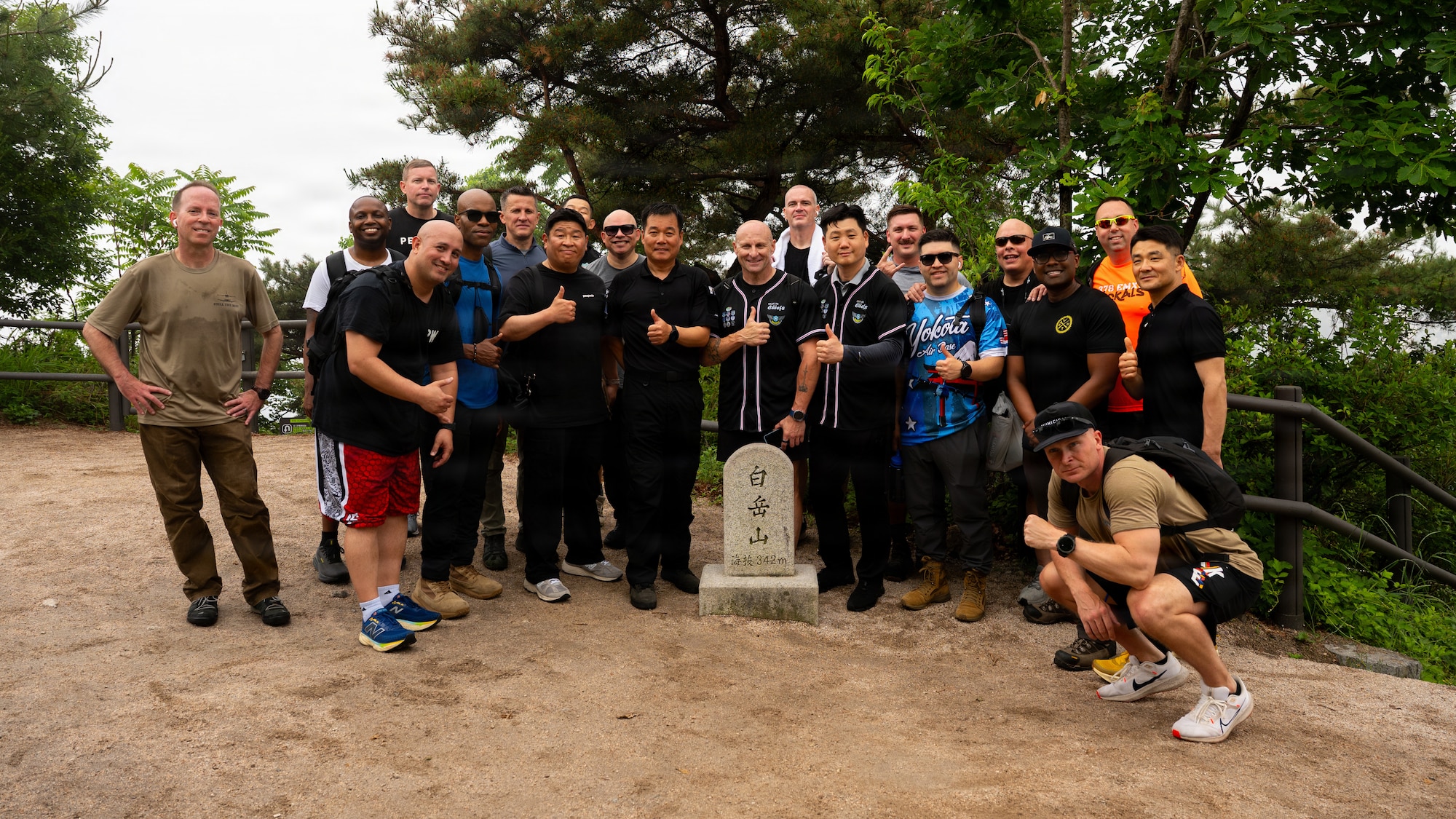 A group of people take a picture at the end point of a hike in front of the stone marker with the meters walked