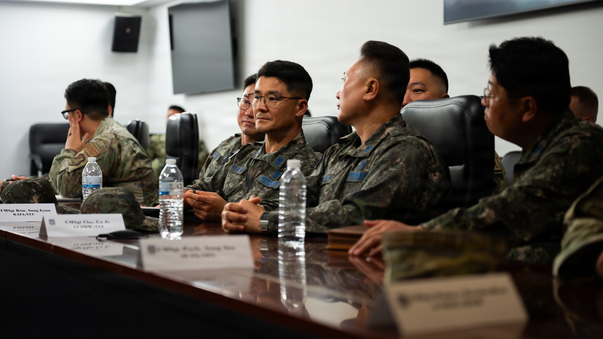 A row of uniformed individuals at a U shaped table in a conference room