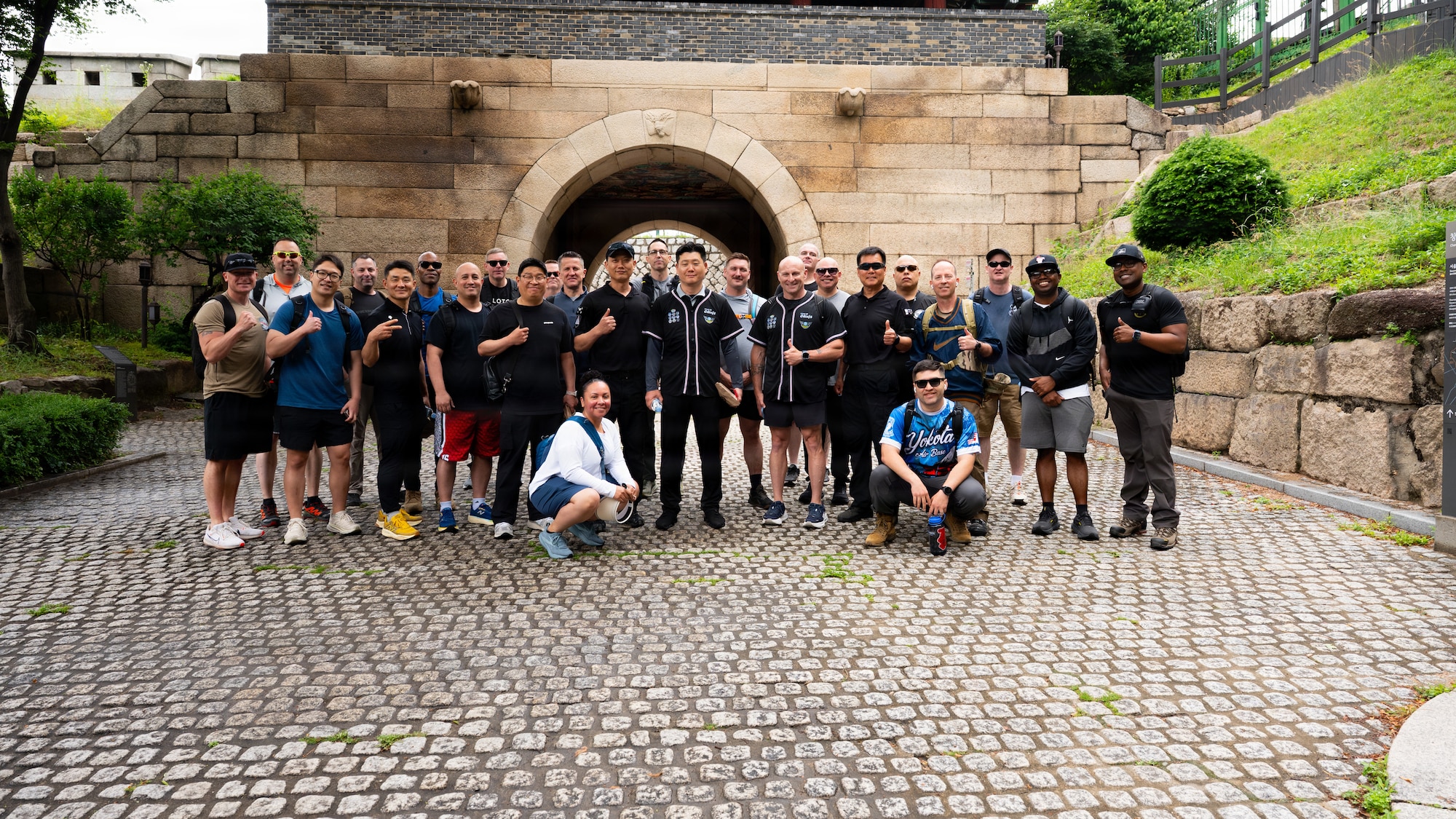 A group of people stand in front a brick structure