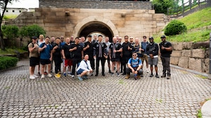 A group of people stand in front a brick structure