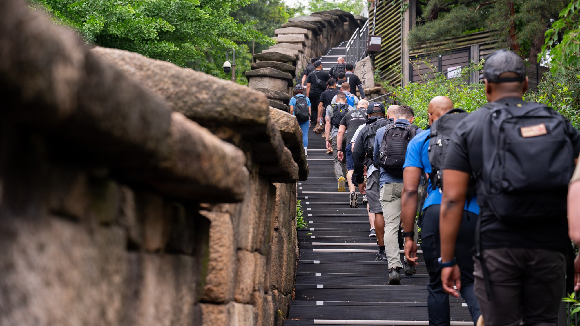 People walking up stairs along a brick wall