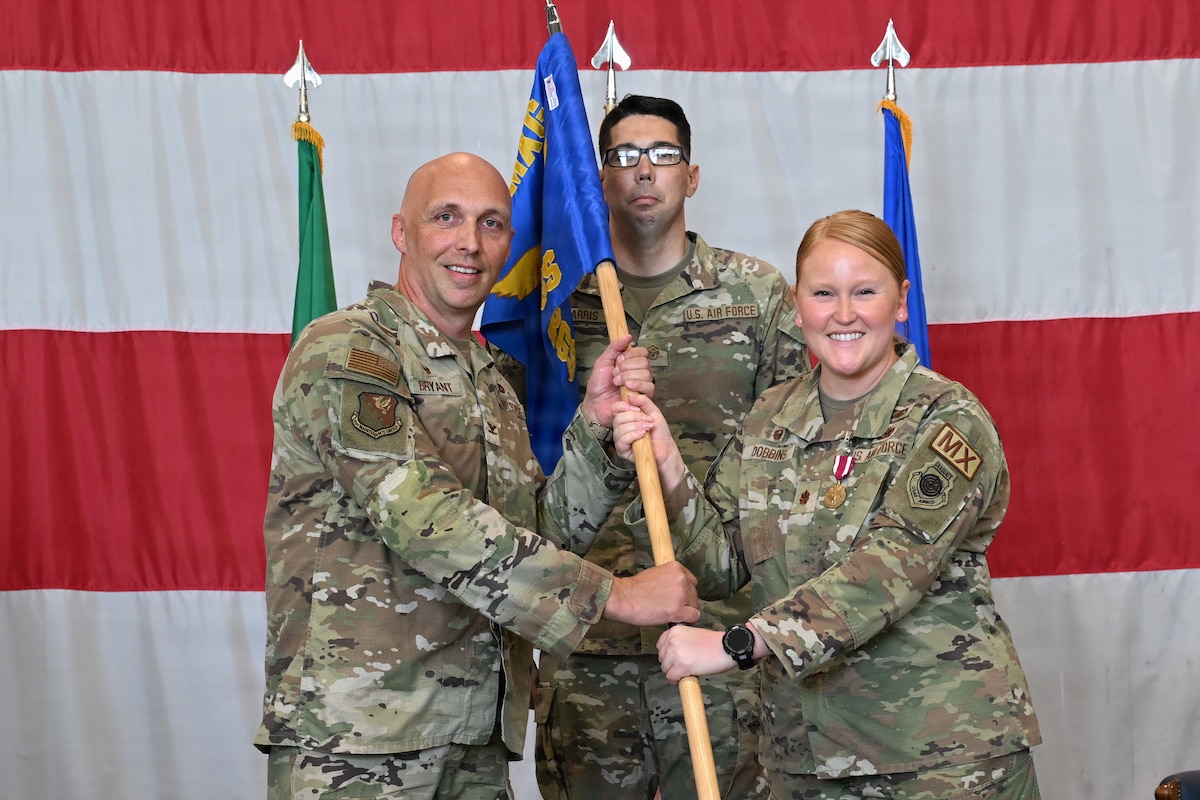 Commander Bryant and Dobbins holds the guidon flag.