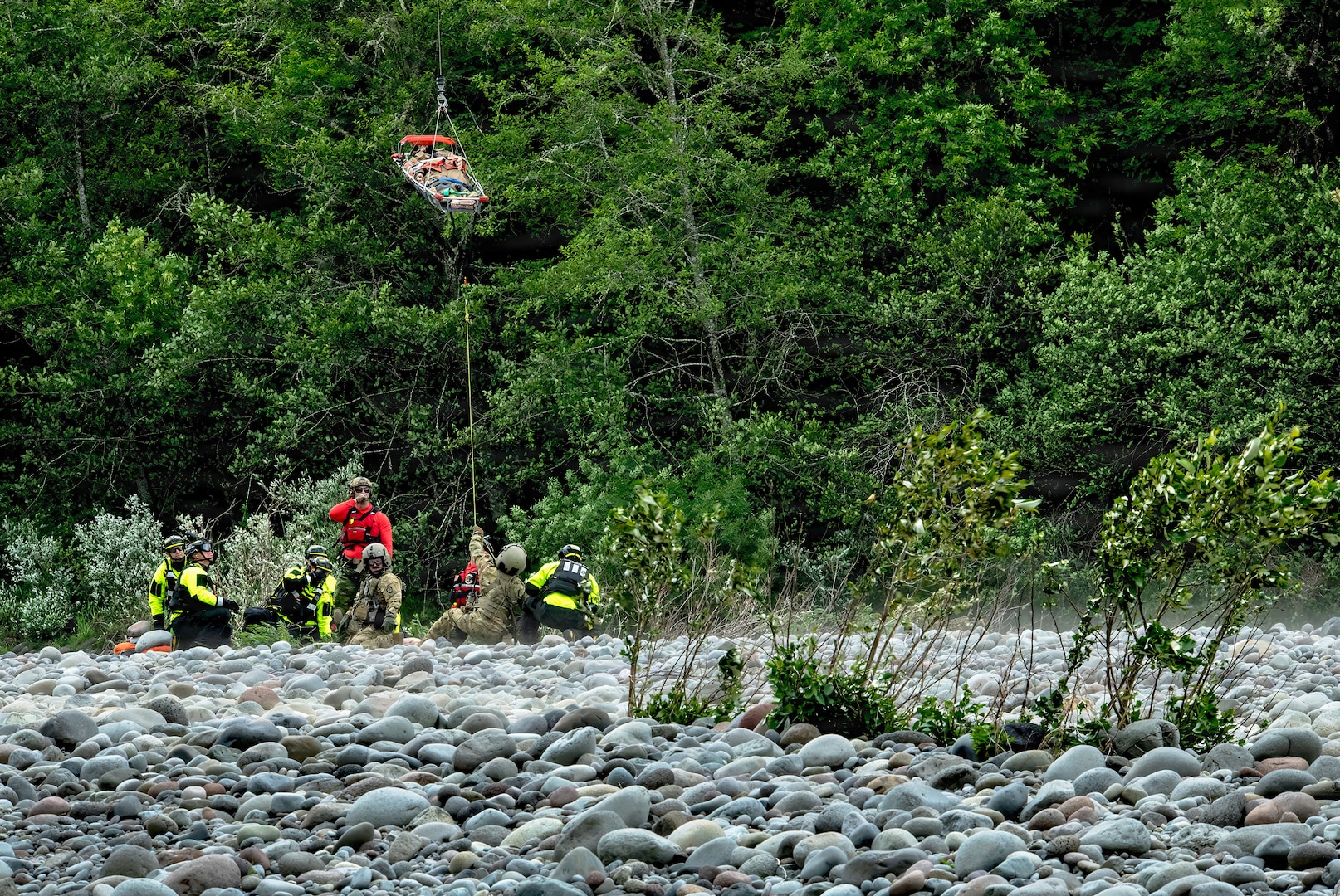 Oregon Army National Guard Flight Medics assigned to G Company, 1-189th Aviation Regiment, along with Clackamas Fire Department responders and Air Force Reserve Pararescuemen from the 304th Rescue Squadron, work together using a rescue litter basket to hoist a simulated injured patient along the Sandy River at Dodge Park in Sandy, Oregon, on June 5, 2026.