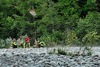 Oregon Army National Guard Flight Medics assigned to G Company, 1-189th Aviation Regiment, along with Clackamas Fire Department responders and Air Force Reserve Pararescuemen from the 304th Rescue Squadron, work together using a rescue litter basket to hoist a simulated injured patient along the Sandy River at Dodge Park in Sandy, Oregon, on June 5, 2026.
