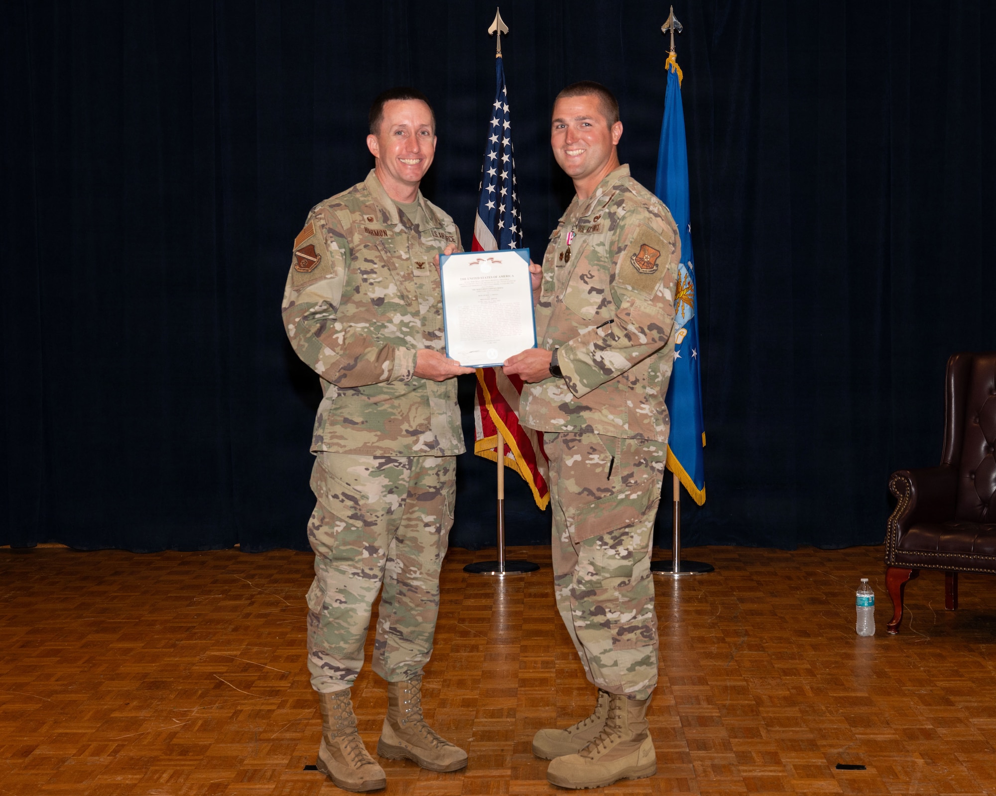 a person passes an award certificate to another person on a stage