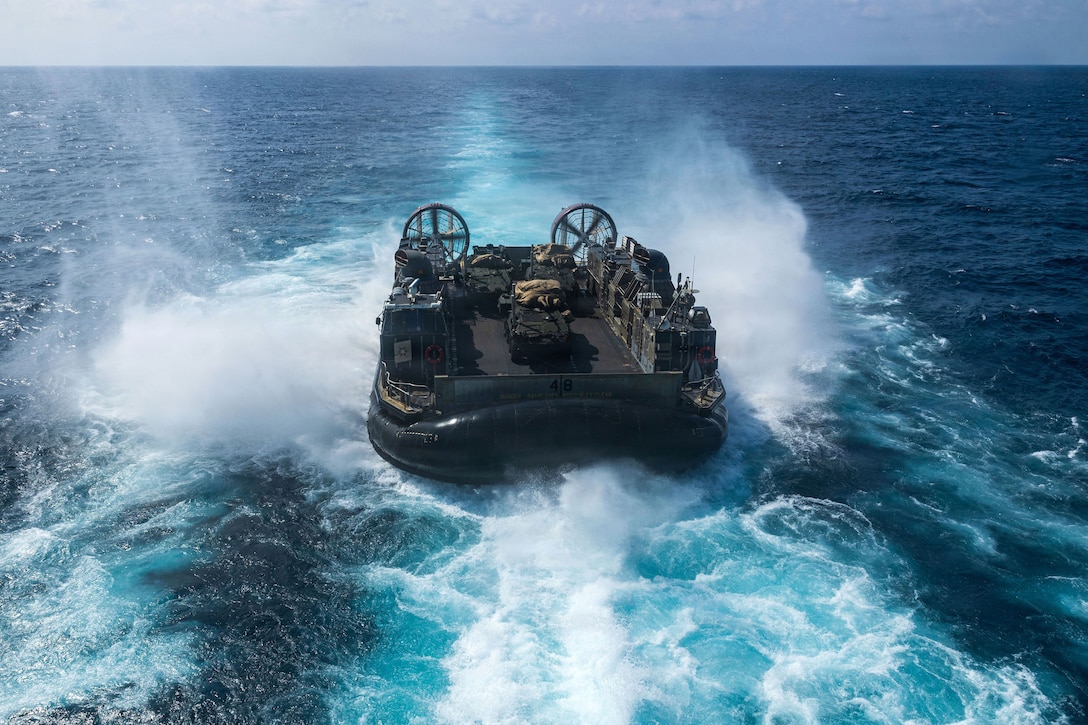 An air-cushioned craft splashes in blue water.