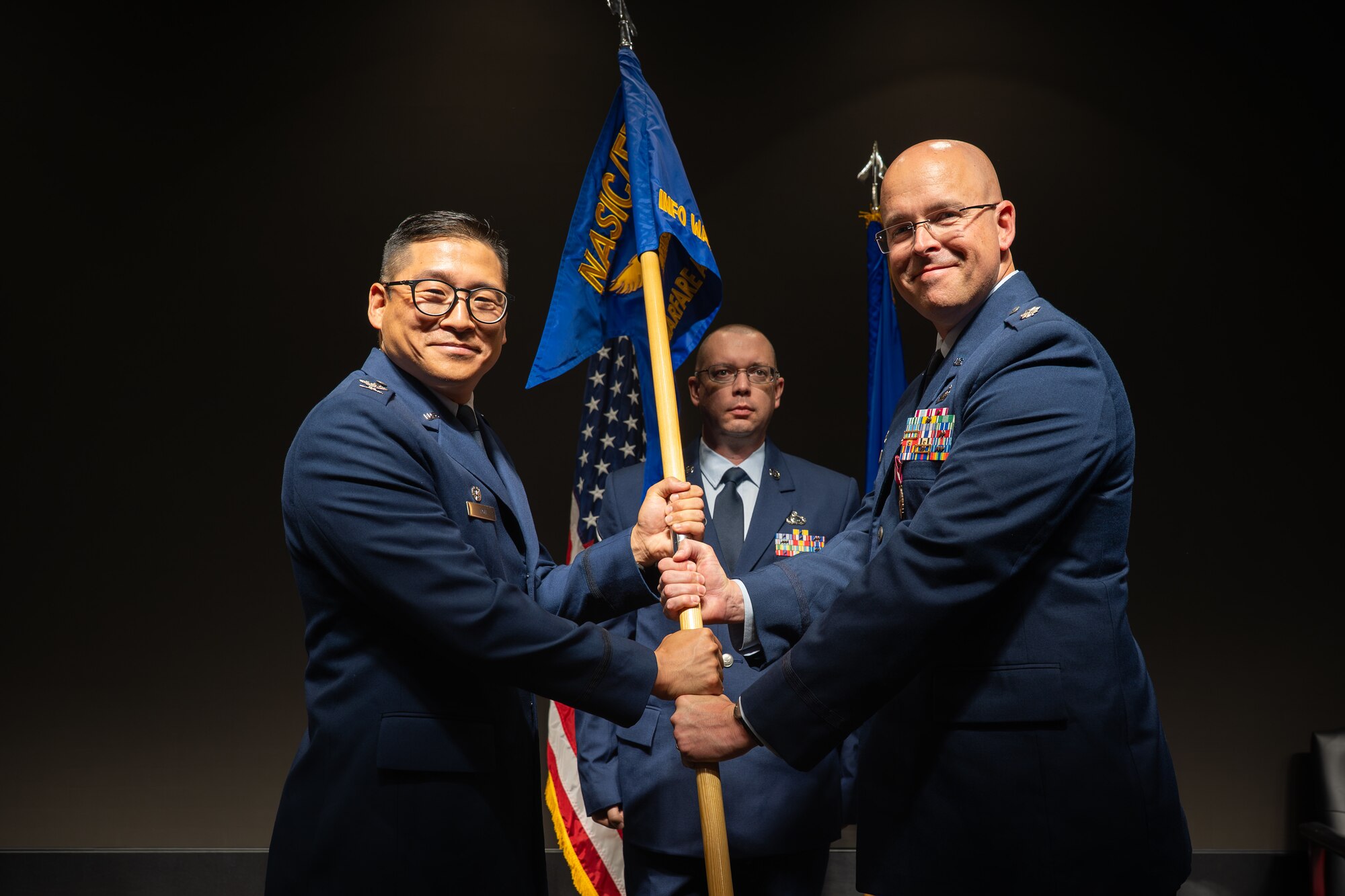 Lt. Col. Neale Linge, right, relinquishes the Information Warfare Analysis Squadron guidon to Col. Gene H. Noh, Forces and Technologies Intelligence Group commander, during a change of command ceremony at the Air Force Institute of Technology, Wright-Patterson Air Force Base, Ohio, June 5, 2026. The squadron drives critical intelligence efforts to identify foreign threats, expose vulnerabilities, and discover strategic opportunities. (U.S. Air Force photo by Staff Sgt. Kristof J. Rixmann)