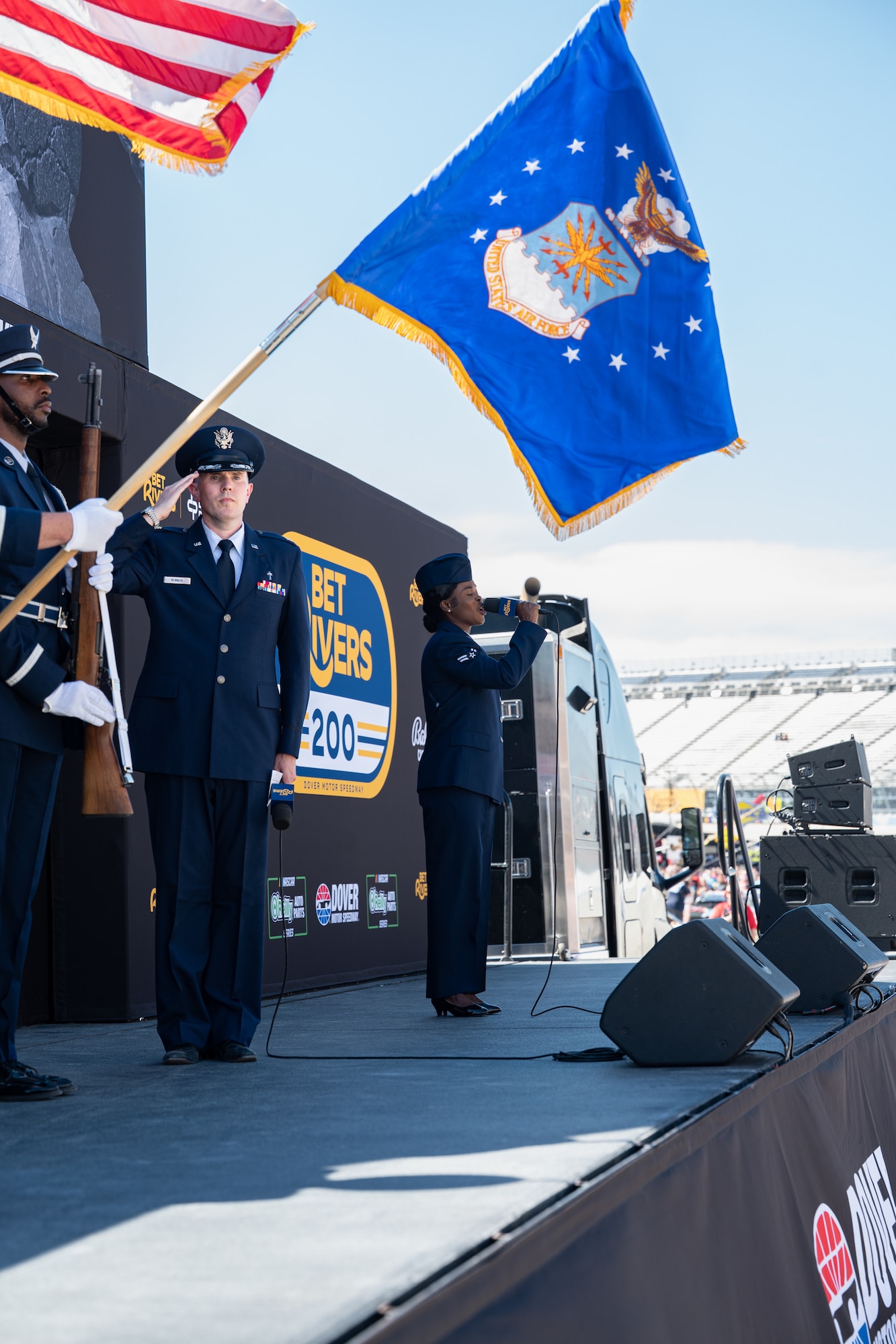 U.S. Air Force Maj. Nathan Newman, 512th Airlift Wing chaplain, salutes the colors while Airman 1st Class Diana Antwi-Boasiako, 436th Medical Group public health apprentice, performs the national anthem at the Dover Motor Speedway in Dover, Delaware, May 16, 2026. The NASCAR O’Reilly Series BetRivers 200 consisted of 38 drivers and two 75-lap segments to determine the racers in the final 200-lap race. (U.S. Air Force photo by Airman 1st Class Macy Dismore-Mann)