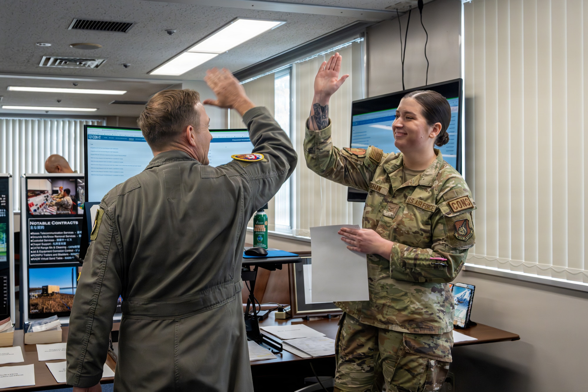 U.S. Air Force Col. Paul Davidson, left, 35th Fighter Wing commander, celebrates the awarding of a contract with Airman 1st Class Katie Kershaw, 35th Contracting Squadron (CONS) contract specialist, during a Wild Weasel Walk-Through.