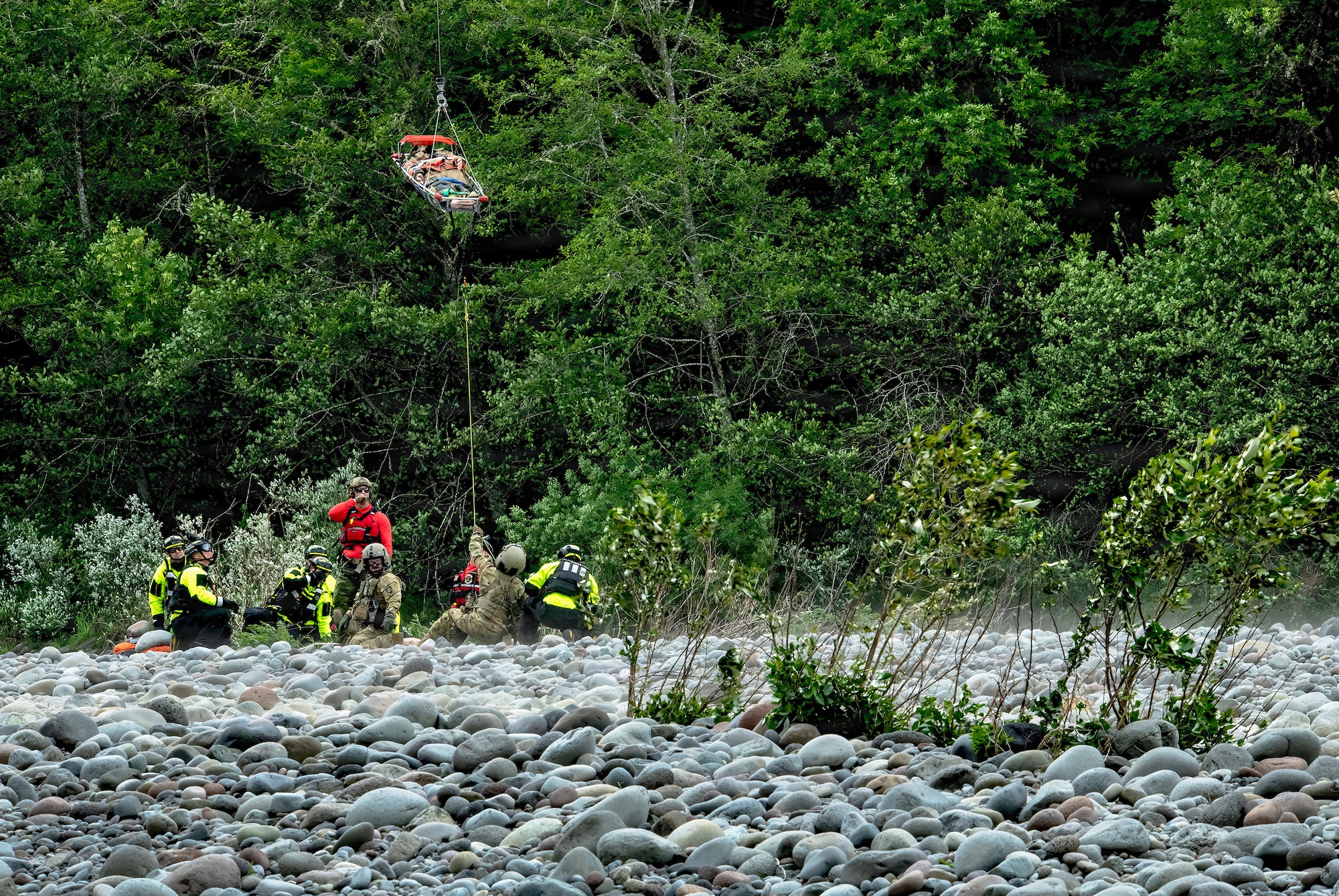 Oregon Army National Guard Flight Medics assigned to G Company, 1-189th Aviation Regiment, along with Clackamas Fire Department responders and Air Force Reserve Pararescuemen from the 304th Rescue Squadron, work together using a rescue litter basket to hoist a simulated injured patient along the Sandy River at Dodge Park in Sandy, Oregon, on June 5, 2026.