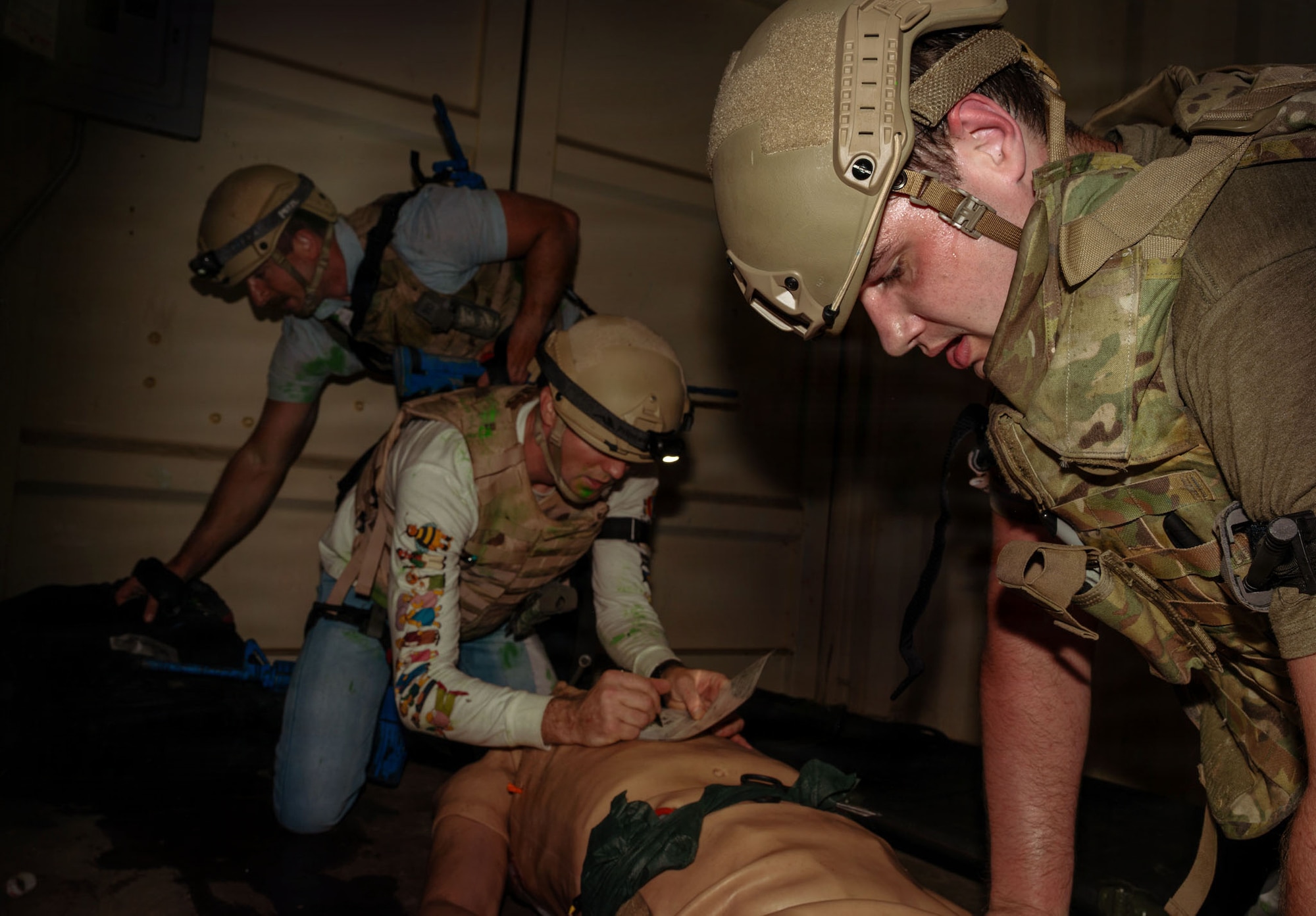 Airmen stand over a training manikin.