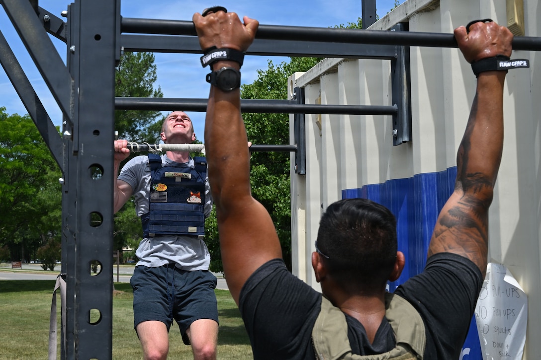 Man in blue weighted vest does a pull-up.