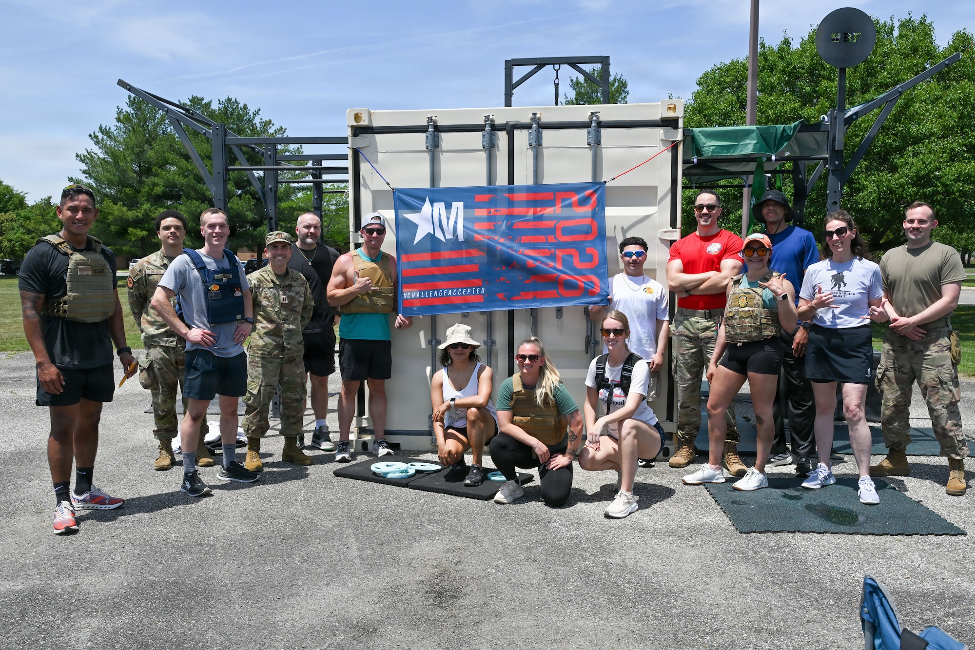 A group poses for a picture in front of a metal container.