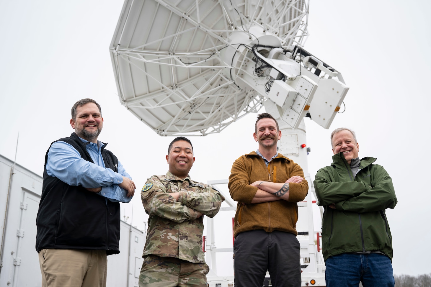 Keith Akins (left), U.S. Naval Research Laboratory (NRL) aerospace engineer, Maj. Joel Atienza (center left), U.S. Space Force (USSF) range integration capability lead, Andrew Phillippi (center right), Exigo program manager, and Byron Hays, Exigo ground system engineer, gather for a group photo with a satellite tracking antenna system at the Blossom Point Tracking Facility in Welcome, Md. March 5, 2026. NRL and USSF partnered to support expanded joint testing and operational readiness for space systems, reinforcing collaboration between the naval and space communities. (U.S. Navy photo by Sarah Peterson)