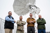 Keith Akins (left), U.S. Naval Research Laboratory (NRL) aerospace engineer, Maj. Joel Atienza (center left), U.S. Space Force (USSF) range integration capability lead, Andrew Phillippi (center right), Exigo program manager, and Byron Hays, Exigo ground system engineer, gather for a group photo with a satellite tracking antenna system at the Blossom Point Tracking Facility in Welcome, Md. March 5, 2026. NRL and USSF partnered to support expanded joint testing and operational readiness for space systems, reinforcing collaboration between the naval and space communities. (U.S. Navy photo by Sarah Peterson)