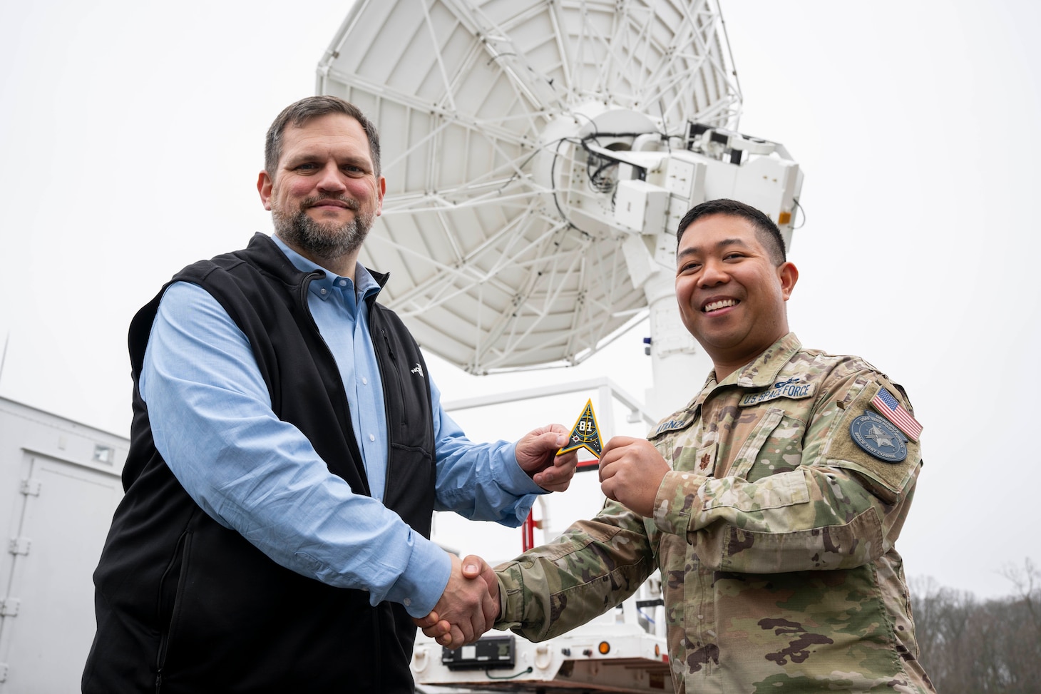Keith Akins (left), U.S. Naval Research Laboratory (NRL) aerospace engineer, and Maj. Joel Atienza, U.S. Space Force (USSF) range integration capability lead, pose for a photo with a satellite tracking antenna system at the Blossom Point Tracking Facility in Welcome, Md. March 5, 2026. NRL and USSF partnered to support expanded joint testing and operational readiness for space systems, reinforcing collaboration between the naval and space communities. (U.S. Navy photo by Sarah Peterson)