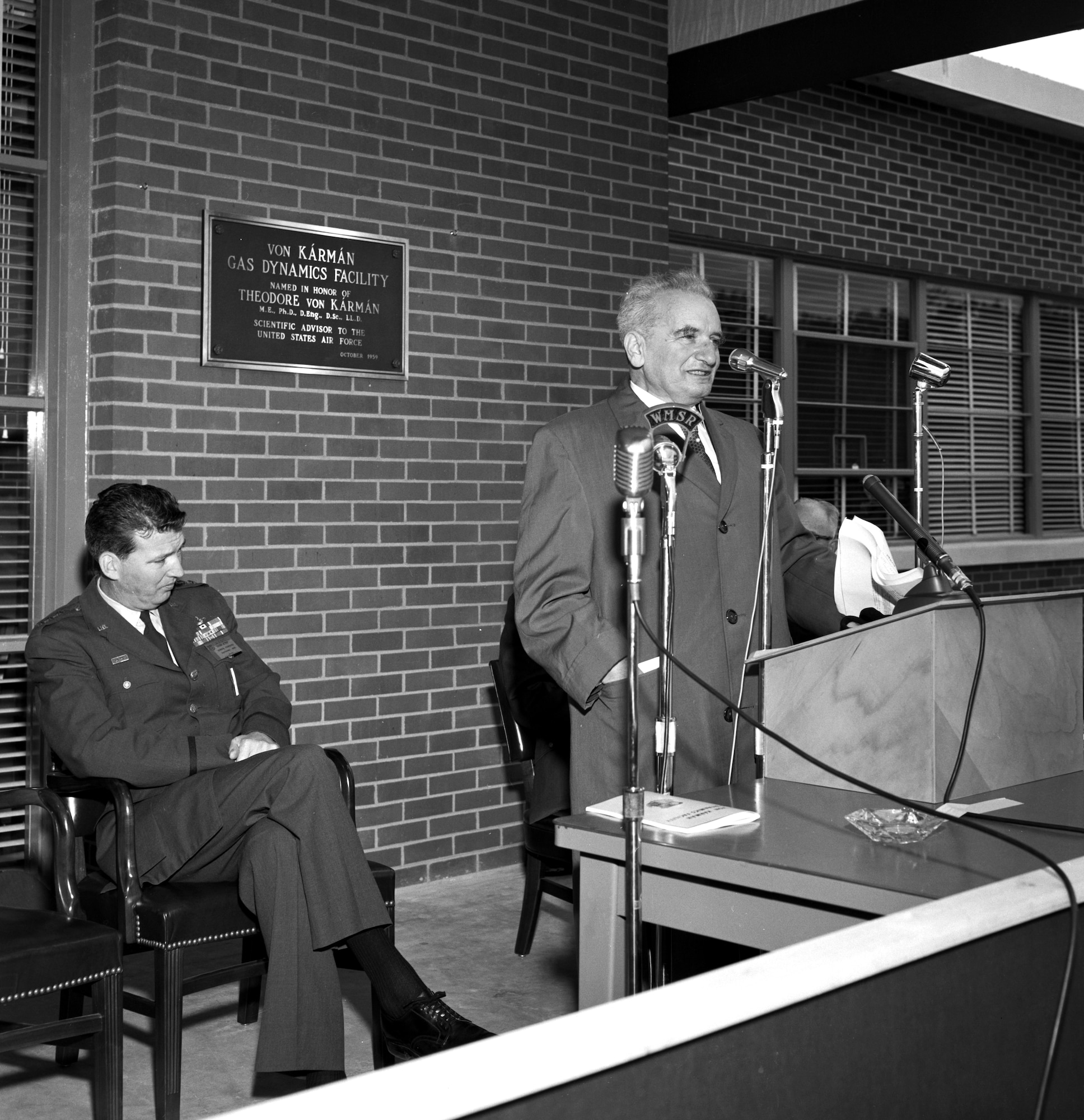 Theodore von Kármán speaks during the dedication of the von Kármán Gas Dynamics Facility at Arnold Air Force Base, Tenn., Oct. 30, 1959. The dedication of the facility in von Kármán’s honor marked the first time the Air Force named a major facility after a living individual. Von Kármán is credited with helping advance U.S. aerospace capabilities. Seated to von Kármán’s right is Gen. Bernard Schriever, then commander of the Air Research and Development Command. (U.S. Air Force photo)