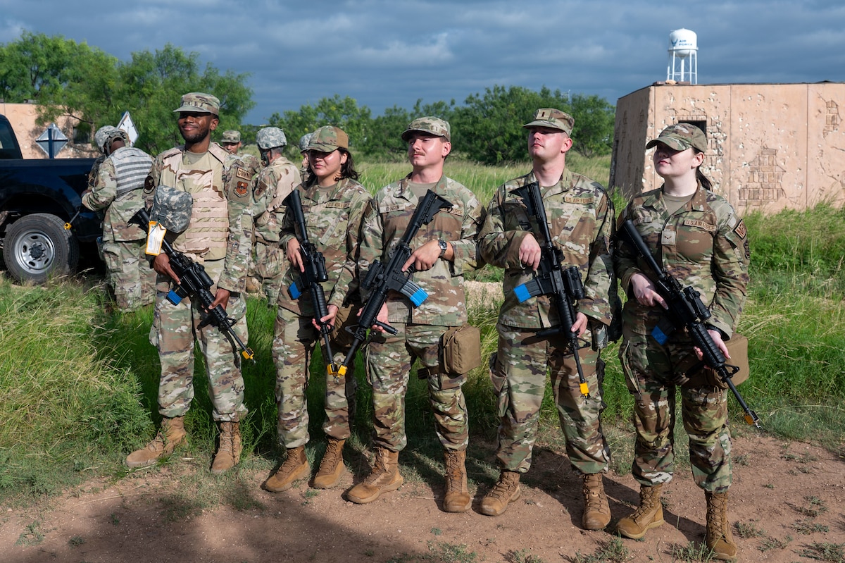 Members of the 17th Training Wing pose for a picture with M4 carbines fitted with training devices during the inaugural Ready Airman Training Day at Goodfellow Air Force Base, Texas, Aug. 8, 2026. Each participant was responsible for an M4 carbine throughout the entire training day, to build the accountability and handling discipline expected in deployed environments. (U.S. Air Force photo by Senior Airman James Salellas)