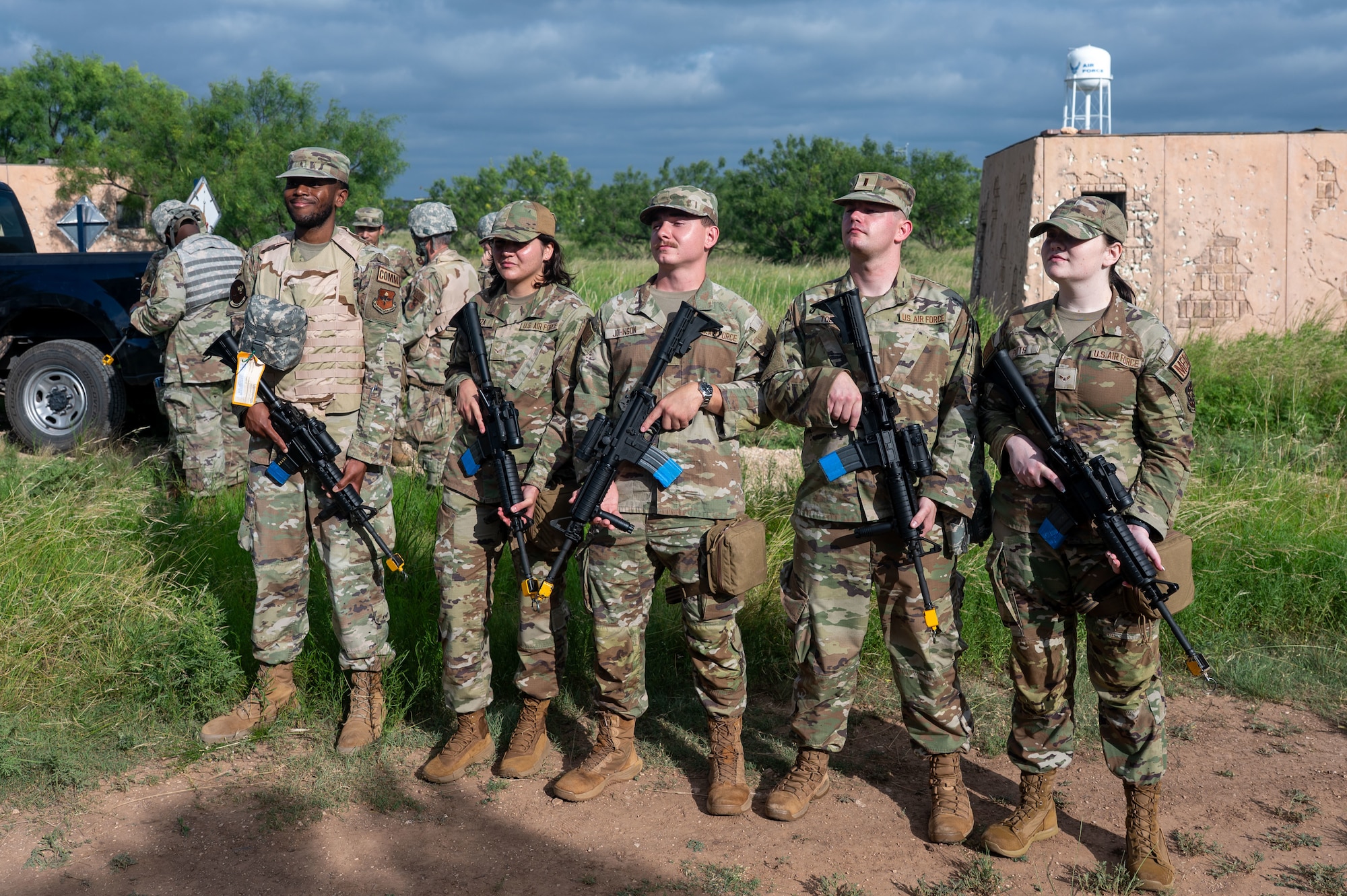 Members of the 17th Training Wing pose for a picture with M4 carbines fitted with training devices during the inaugural Ready Airman Training Day at Goodfellow Air Force Base, Texas, Aug. 8, 2026. Each participant was responsible for an M4 carbine throughout the entire training day, to build the accountability and handling discipline expected in deployed environments. (U.S. Air Force photo by Senior Airman James Salellas)