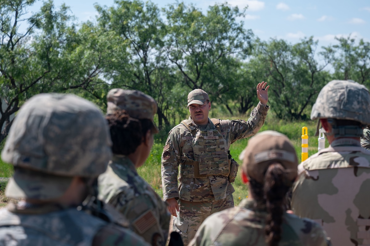 U.S. Air Force Tech. Sgt. Jeremy Tarrats, 17th Security Forces defender,  briefs participants on checkpoint procedures during the inaugural Ready Airman Training Day at Goodfellow Air Force Base, Texas, Aug. 8, 2026. The checkpoint scenario required Airmen to balance security measures before reacting to a simulated attack, testing split-second decision-making under conditions designed to replicate real-world engagements. (U.S. Air Force photo by Senior Airman James Salellas)