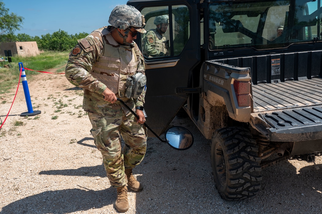 U.S. Air Force Staff Sgt. Orlando Lorenzano Jr., 17th Civil Engineer Squadron execution support noncommissioned officer in charge, conducts an under-vehicle inspection as part of the inaugural Ready Airman Training Day at Goodfellow Air Force Base, Texas, Aug. 8, 2026. The checkpoint evolution required participants to demonstrate specific, observable security behaviors under stress before reacting to a simulated hostile act. (U.S. Air Force photo by Senior Airman James Salellas)