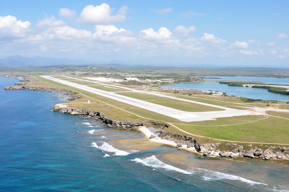 An empty aviation runway is situated with water on both sides.