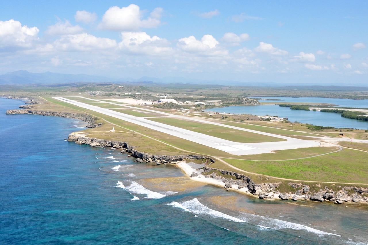 An empty aviation runway is situated with water on both sides.