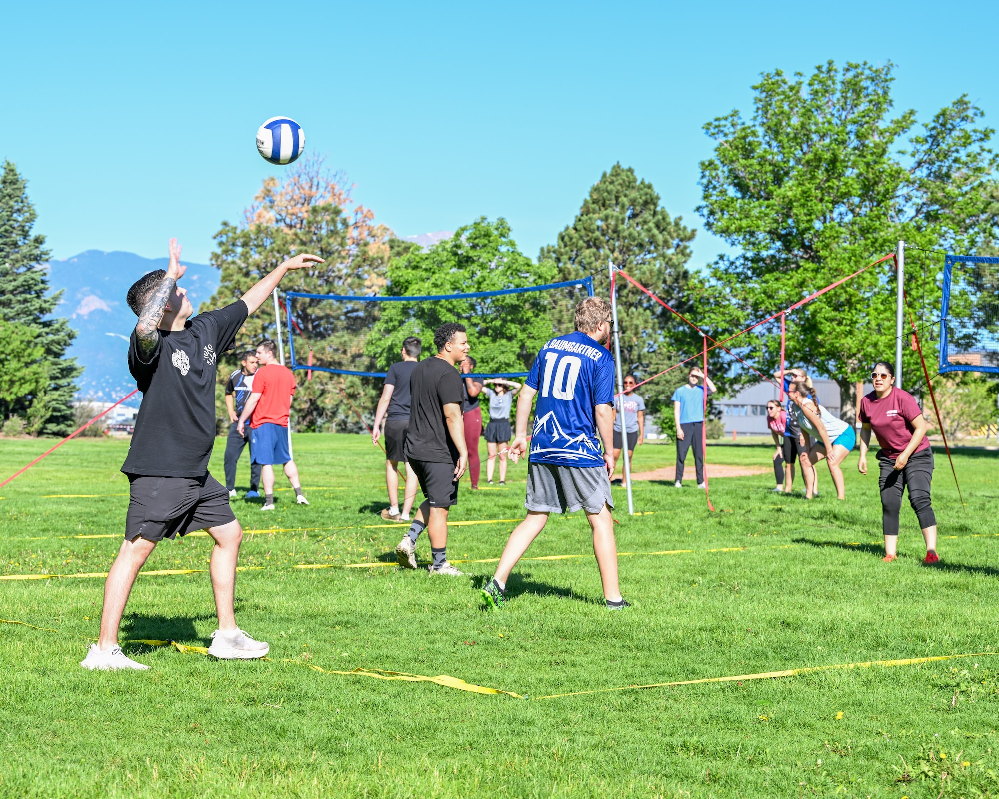 A player winds up to serve a volleyball, while he's team is waiting for the match to start.