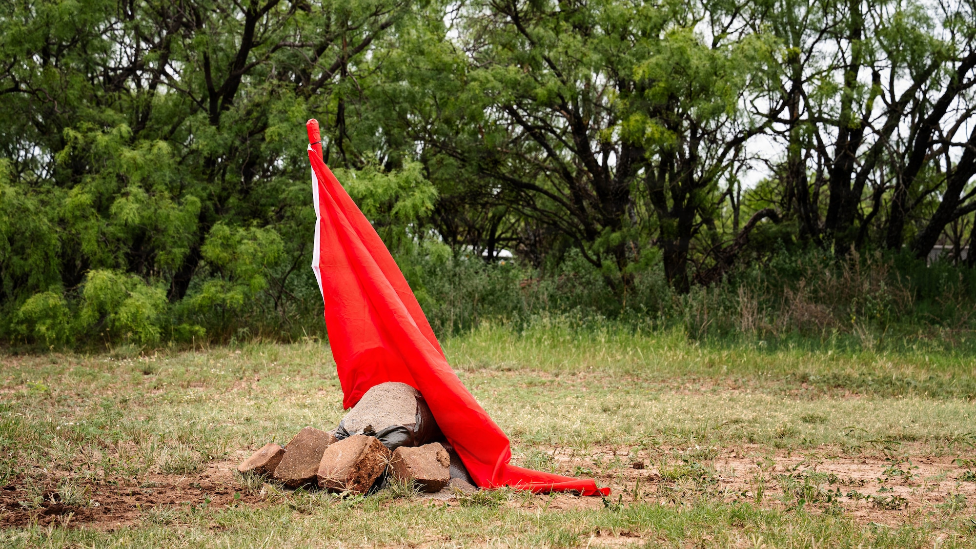 Airmen participate in a field exercise and play capture the flag outside in a wooded area