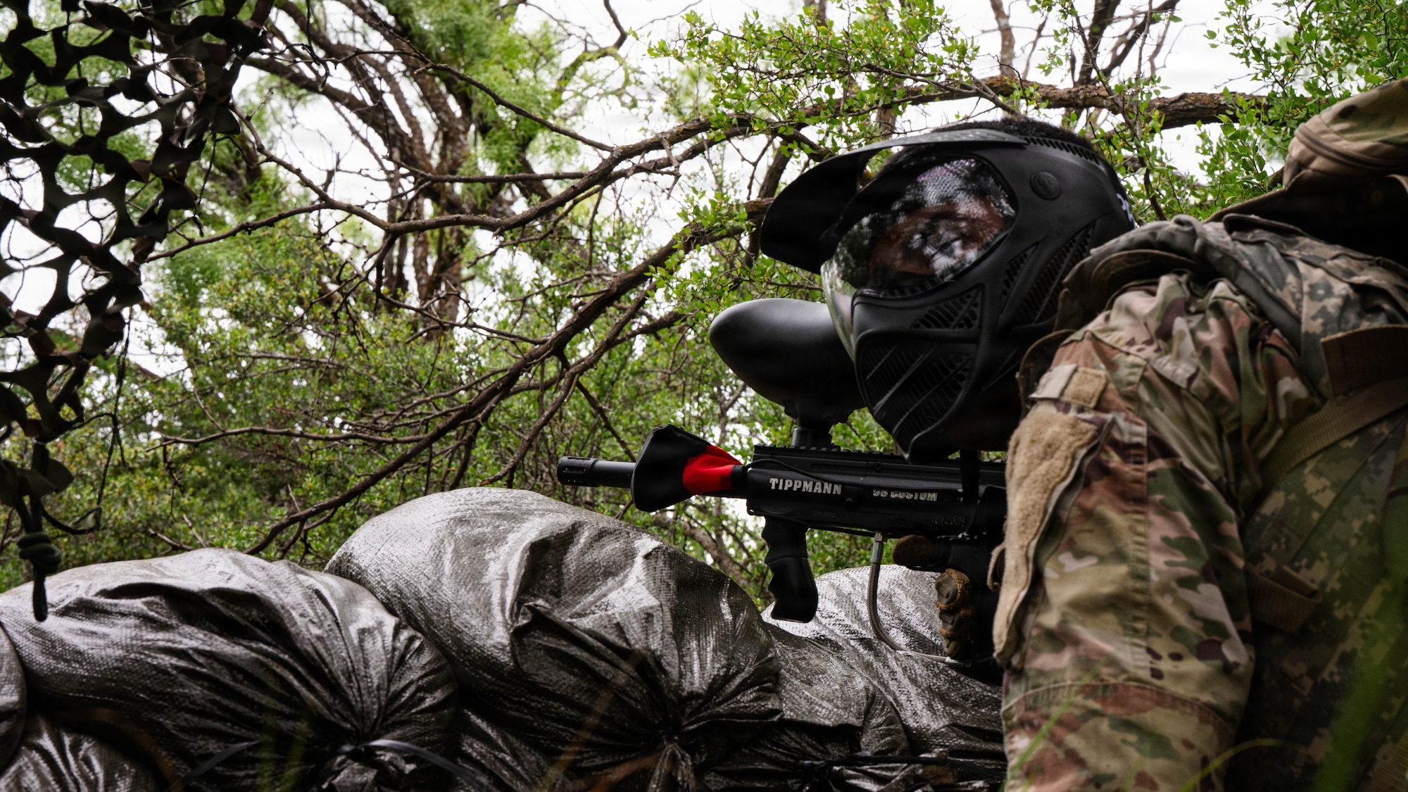 Airmen participate in a field exercise and play capture the flag outside in a wooded area