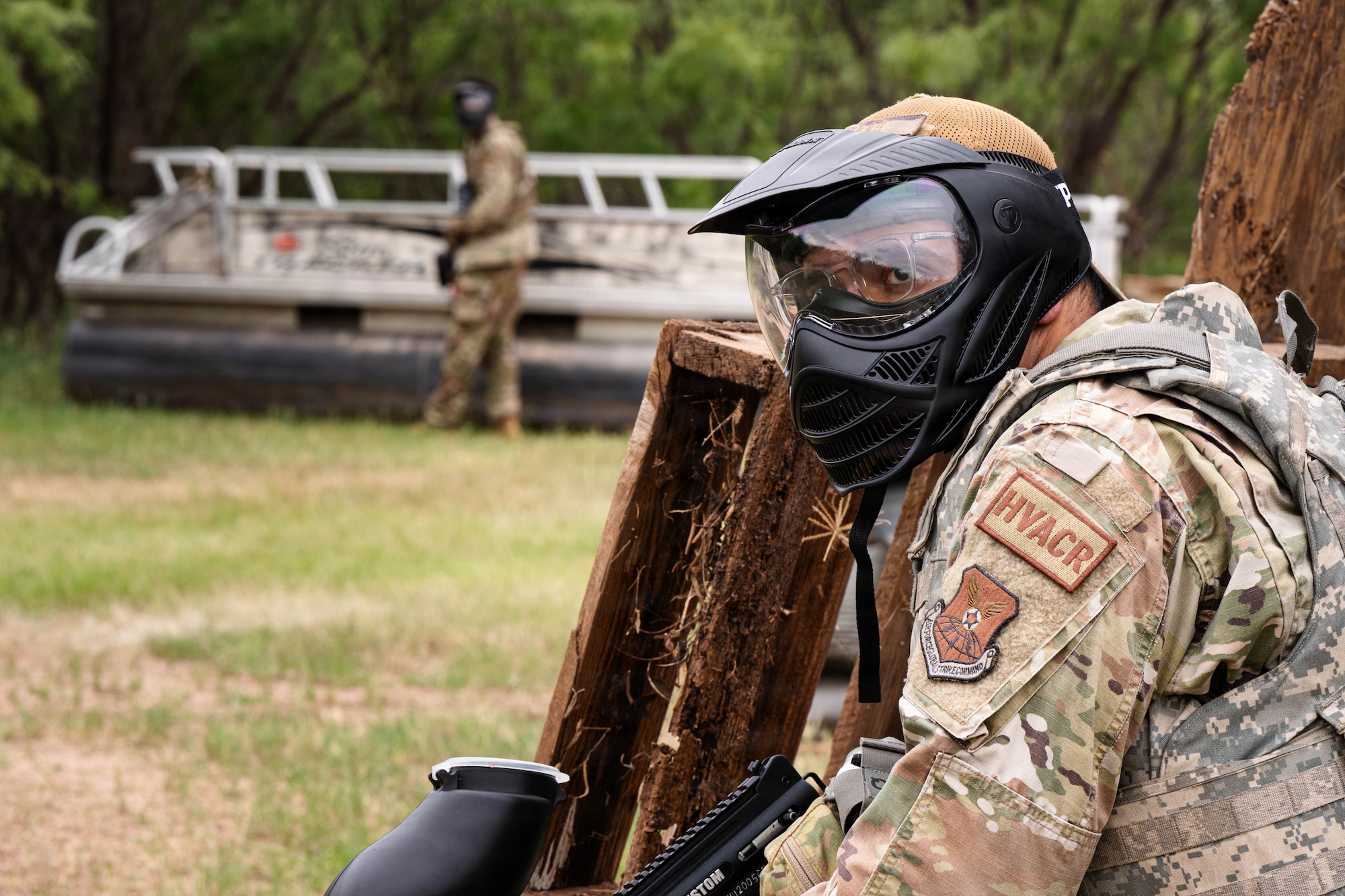 Airmen participate in a field exercise and play capture the flag outside in a wooded area