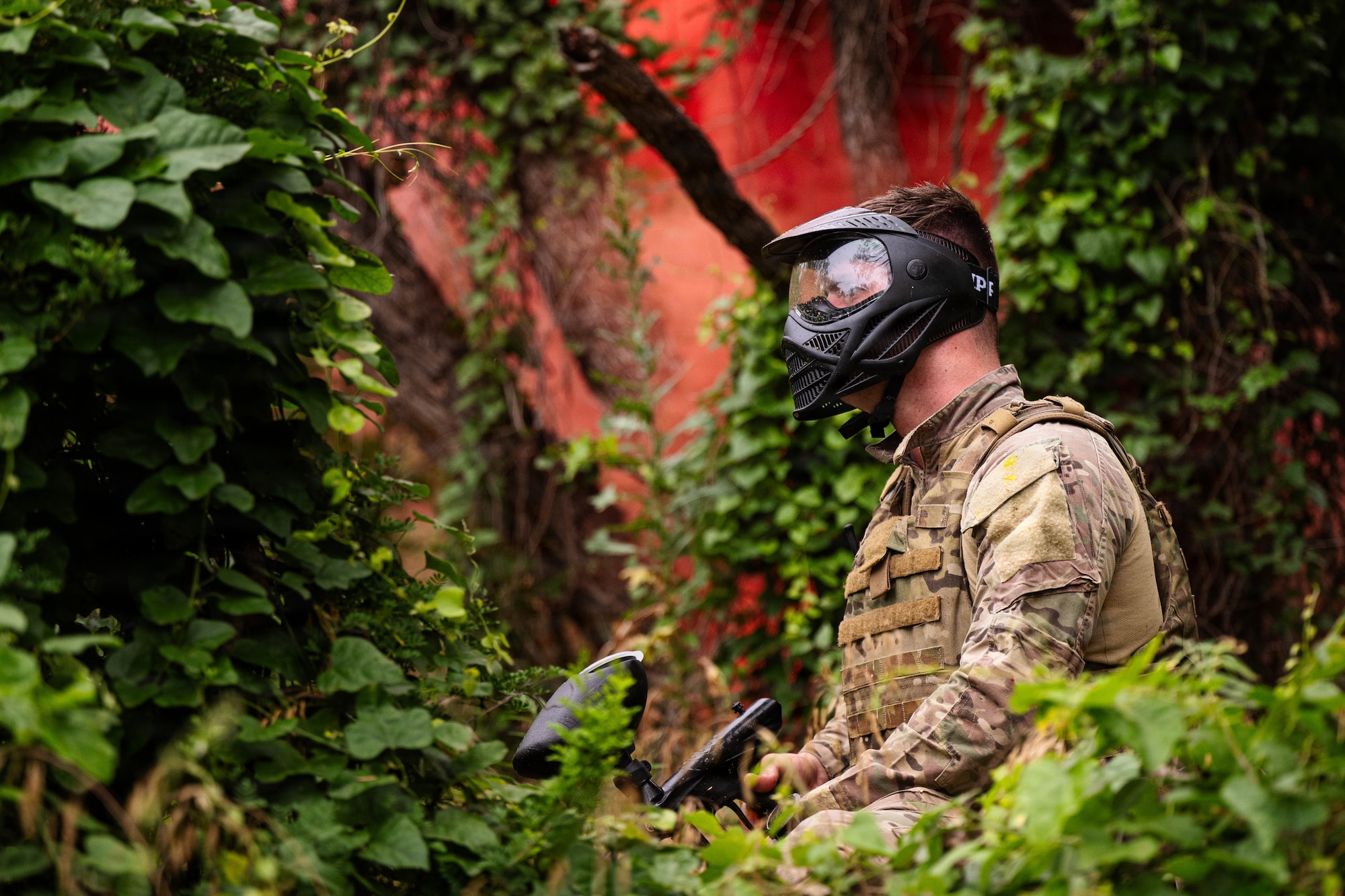 Airmen participate in a field exercise and play capture the flag outside in a wooded area