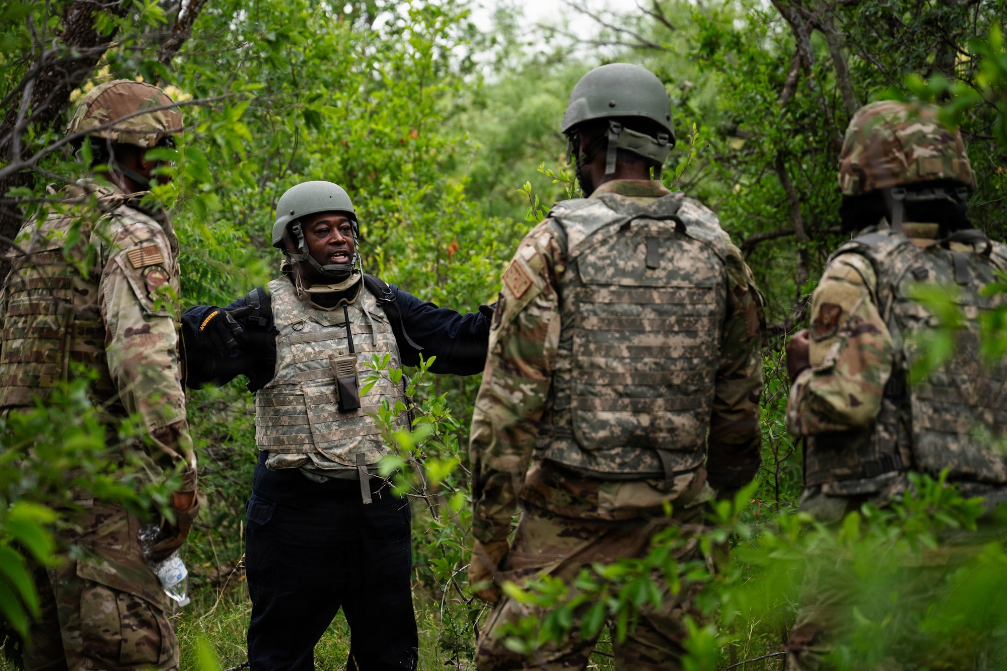 Airmen participate in a field exercise and play capture the flag outside in a wooded area