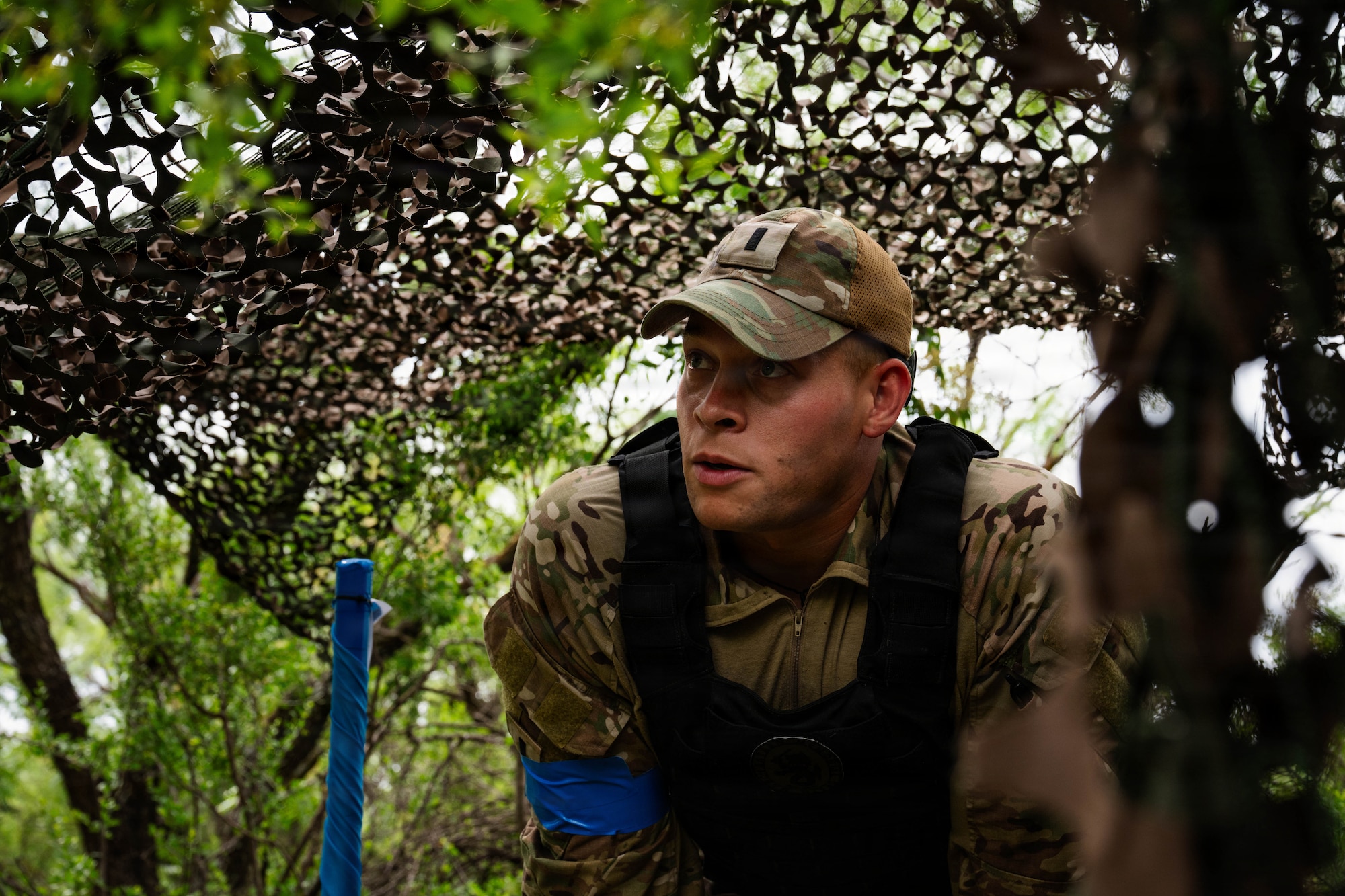 Airmen participate in a field exercise and play capture the flag outside in a wooded area