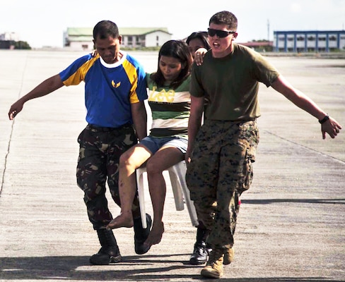 Marine Corps Lance Cpl. John Robertson, right, a landing support specialist with the 3rd Marine Expeditionary Brigade, and members of the Armed Forces of the Philippines assist a civilian displaced by Typhoon Haiyan as part of Operation Damayan at Villamor Air Base, Nov. 14, 2013. U.S. Marine Corps photo by Lance Cpl. Anne K. Henry
