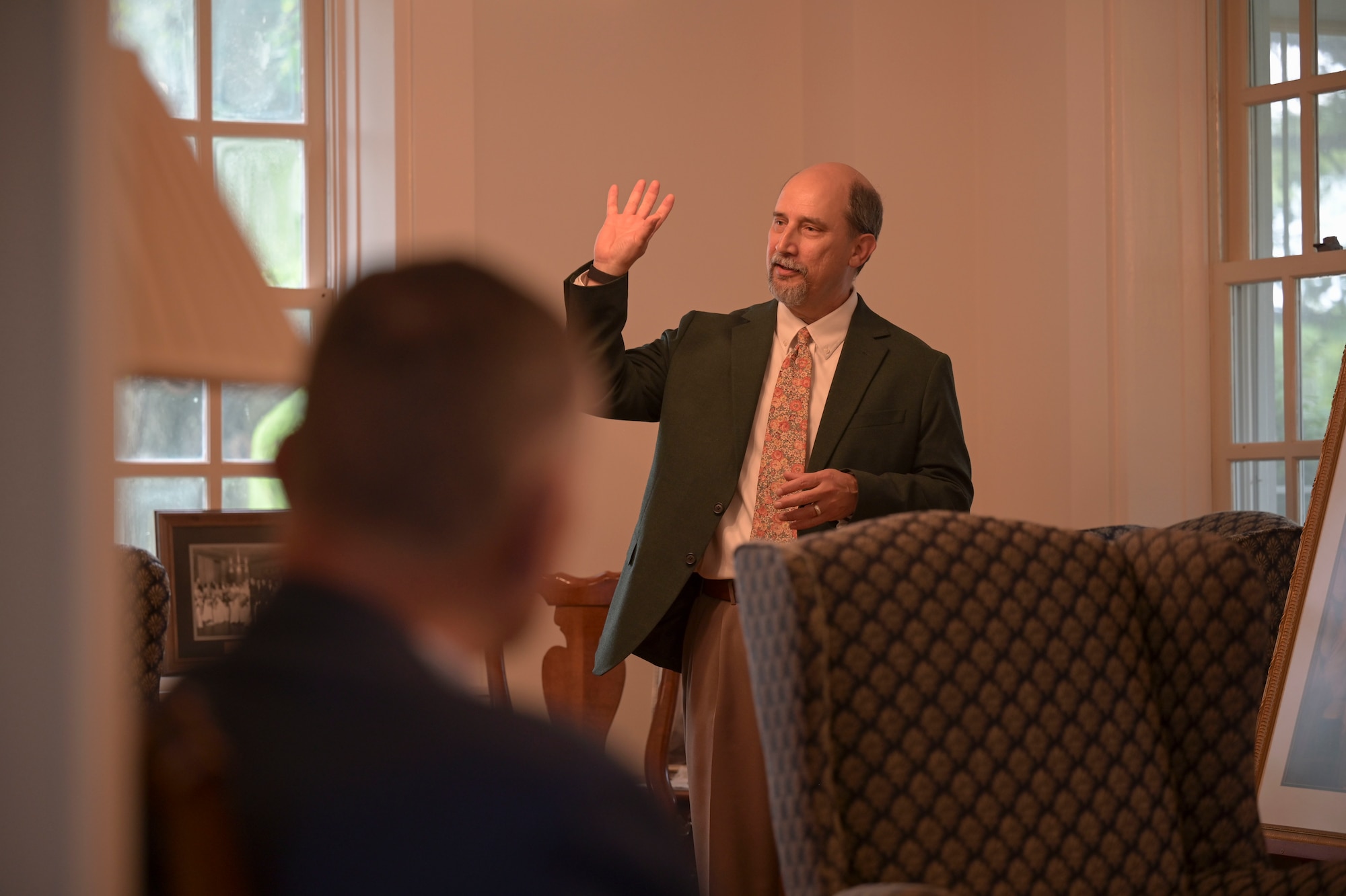 A man in a suit and tie briefs a room of induvial