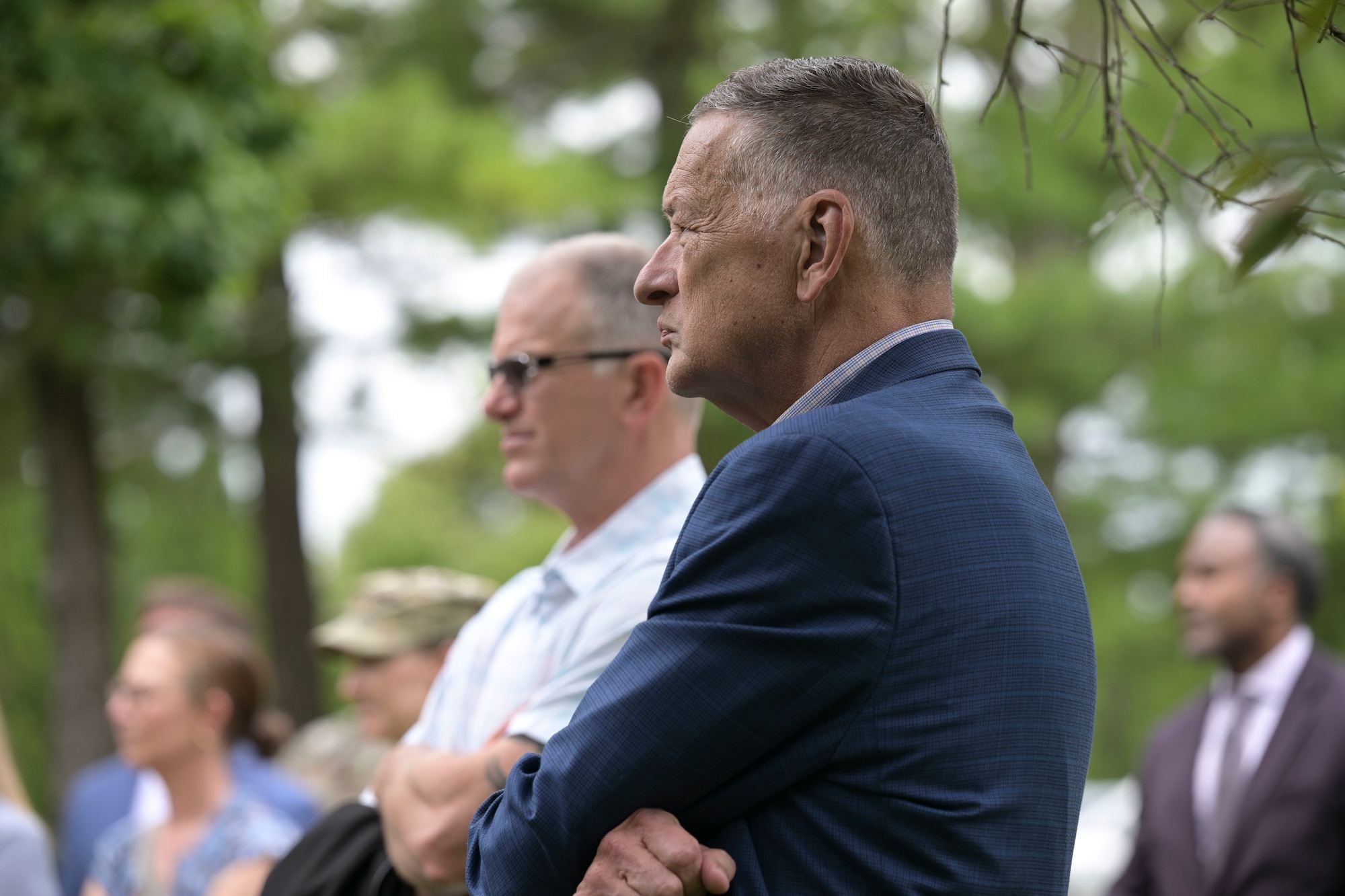 A man in a navy-blue suit stands outdoors