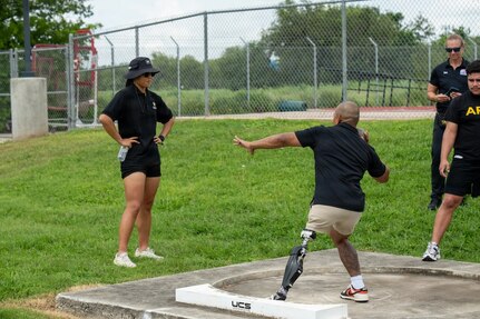 U.S. Army Staff Sgt. Gene Calantoc competes in a shot put training event while Team Army coaches and support personnel observe.