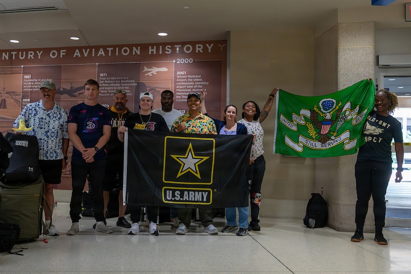 Team Army competitors pose for a group with U.S. Army flags photo after arriving at San Antonio International Airport for the 2026 Warrior Games June 8, 2026.