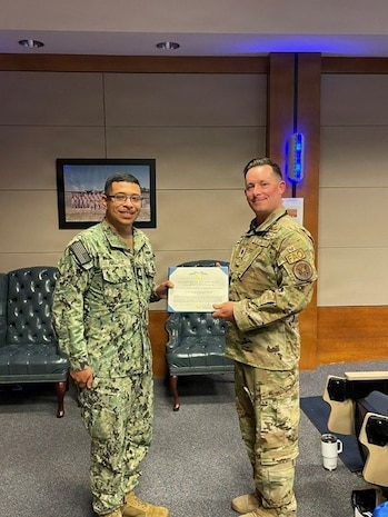 Travis Air Force Base – Chief Petty Officer Darren Hallhuz (left), a missile technician assigned to Defense Threat Reduction Agency (DTRA) Global Threat Reduction Directorate (GT), receives the Navy and Marine Corps Achievement Medal on May 20, 2026 at Travis Air Force Base in Fairfield, California.  The award was presented by Lt. Col. Ronald J. Barnhart (right), DTRA GT’s Travis commanding officer,  on behalf of Portfolio Acquisition Executive Strategic Systems Programs Program Management Office (PMO) Flight Systems detachment (SPF(S)) in recognition of Hallhuz’s exceptional support to the U.S. Navy submarine force throughout SPF(S)’ Reverse Strategic Weapons Systems (SWS) Week. (U.S. Navy photo by Shelby Thompson//Released)