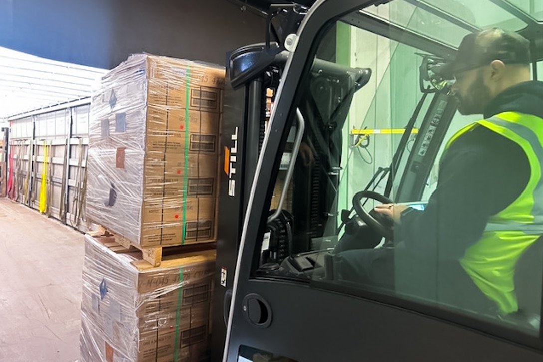Man drives a forklift with palettes on the front