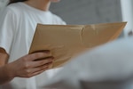 Woman holds yellow envelope package.