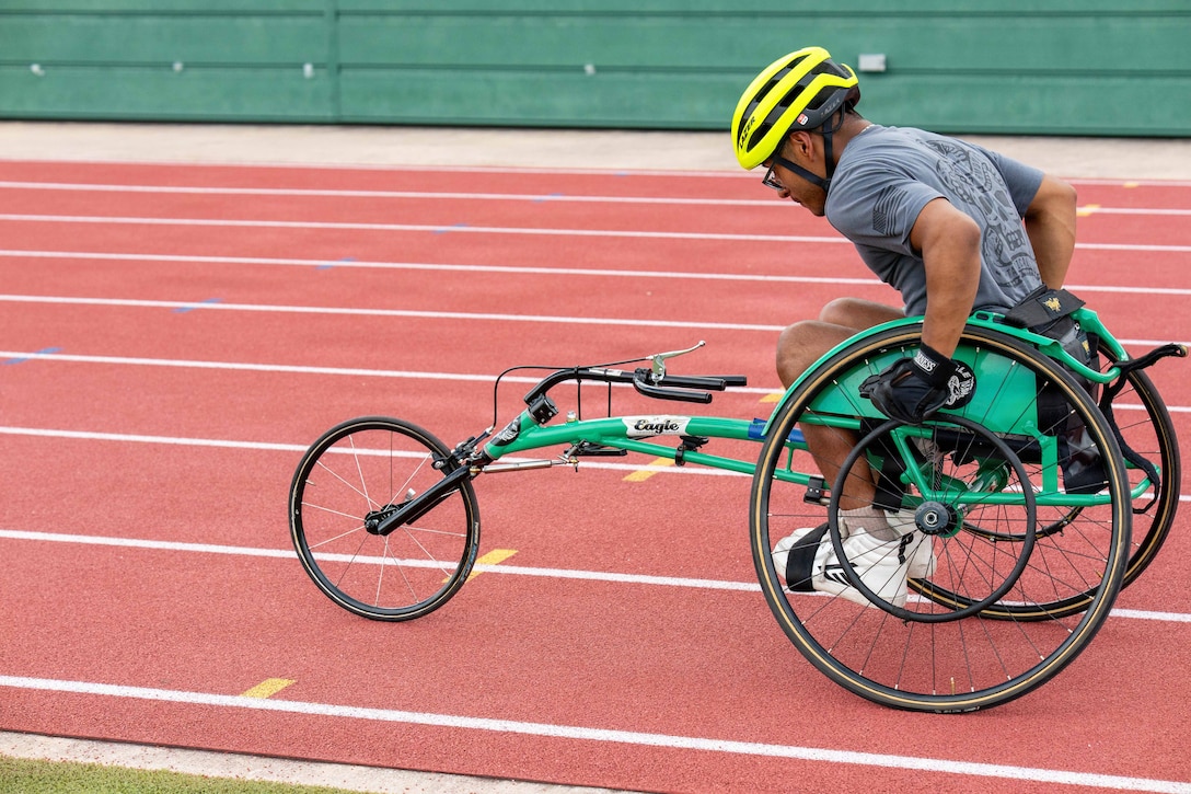 A Team Army competitor uses an adaptive tricycle on a track during the day.