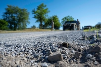 A mock improvised explosive device sits on a gravel road ahead of the 11th Civil Engineer Squadron’s convoy.