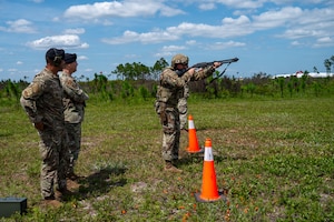 U.S. Air Force Tech. Sgt. Nicholas Rhoades, 325th Security Forces Squadron training and standardization section chief, right, aims an M870 shotgun as Maj. Gen. Thomas P. Sherman, Air Force Installation and Mission Support Center commander, and Senior Master Sgt. Reginald Walters, 325th SFS future operations superintendent, observe at Tyndall Air Force Base, Florida, June 3, 2026. During the demonstration, Rhoades engaged simulated aerial targets to highlight the squadron's evolving capability to neutralize low-altitude, high-speed airborne threats. (U.S. Air Force photo by Airman 1st Class Rosario Garcia)